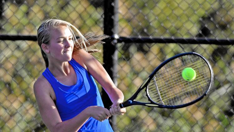 A+woman+holding+a+tennis+racket+getting+ready+to+hit+the+ball