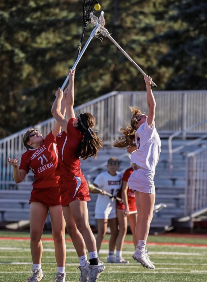 Megan Rocklein (in white) jumping for the ball during a lacrosse game
