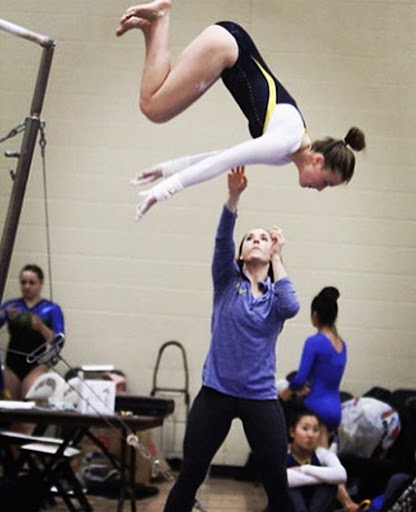 Coach Chana spotting a LFHS athlete on bars at a meet.
Photo courtesy of Chana Wilczynski
