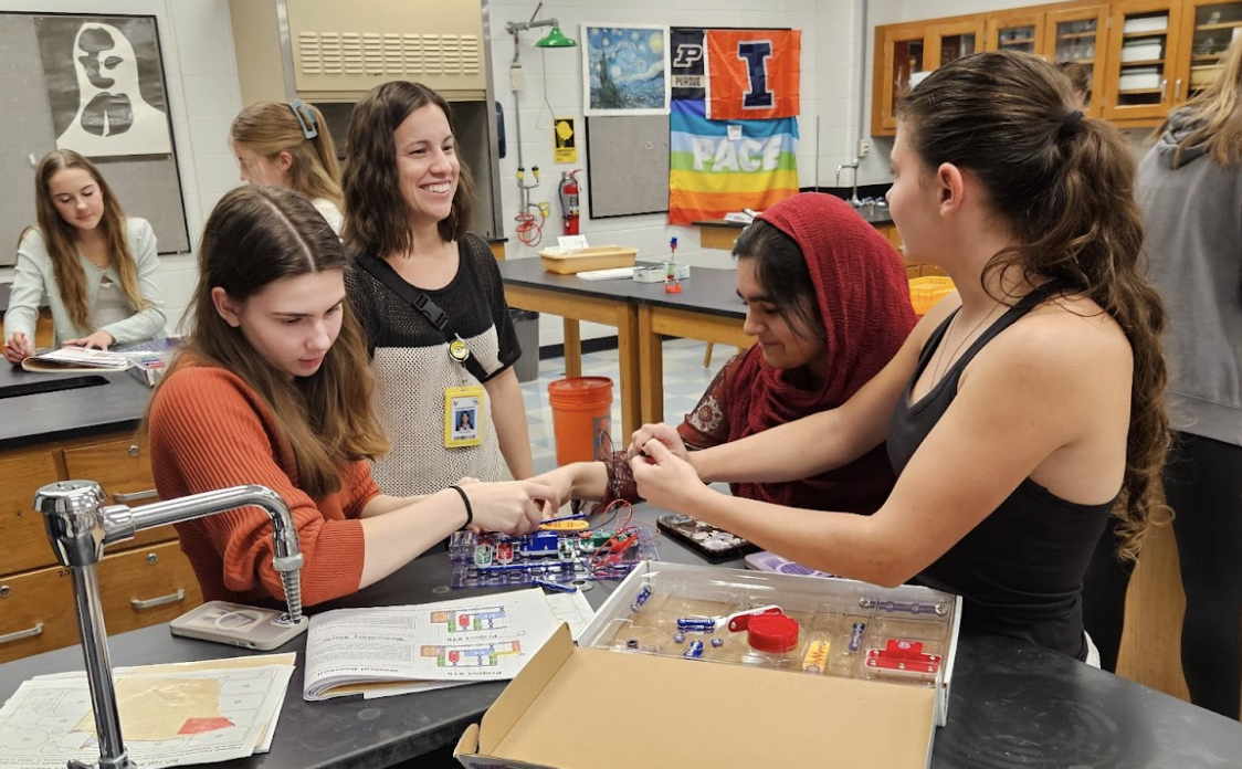 Women in STEM members performing an experiment while discussing with a staff member.