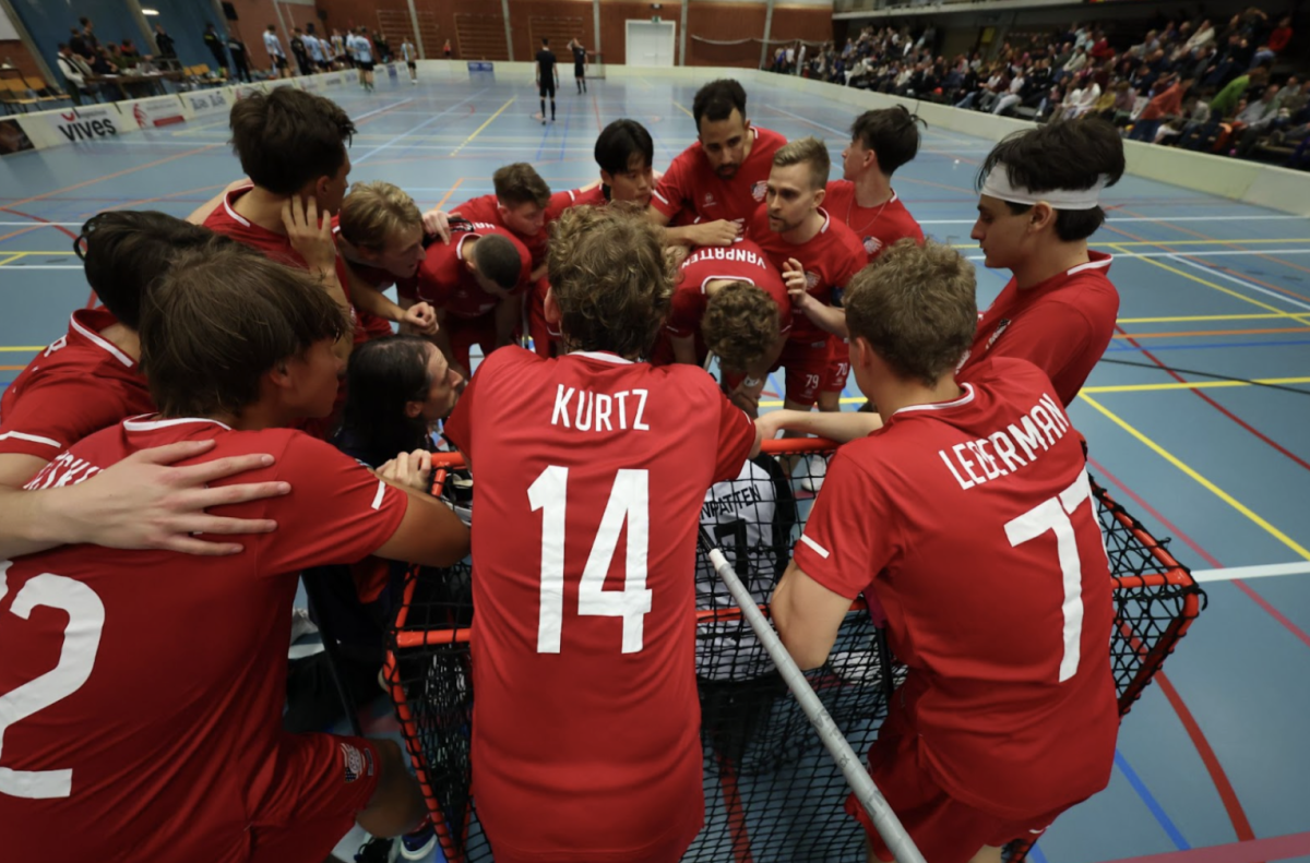 Floorball team huddling around the net.
