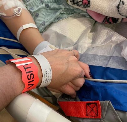 Ms. Kubik holds her daughter's hand in the hospital after the sledding accident.